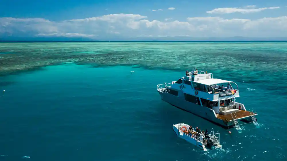 The catamaran and a tender moored over the reef edge