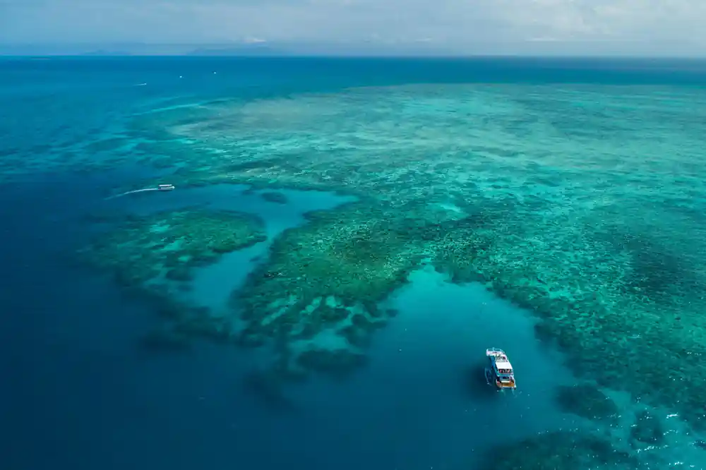 Coral bommies scattered under clear water with a boat moored beyond