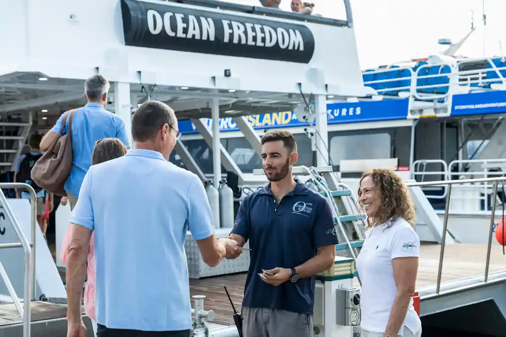 Crew greeting guests at the boarding gate under the Ocean Freedom sign