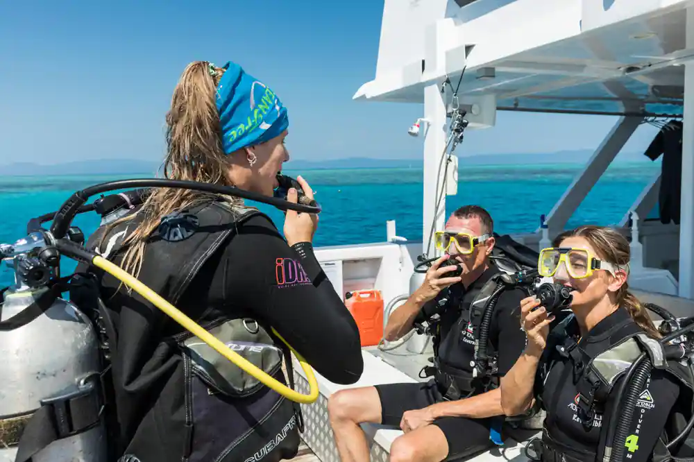 Divers in full gear seated on the dive deck before entering