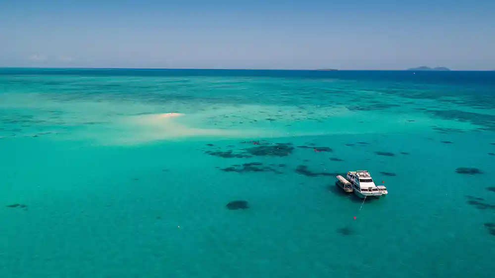 A pale sand cay and reef flat with a boat at its edge