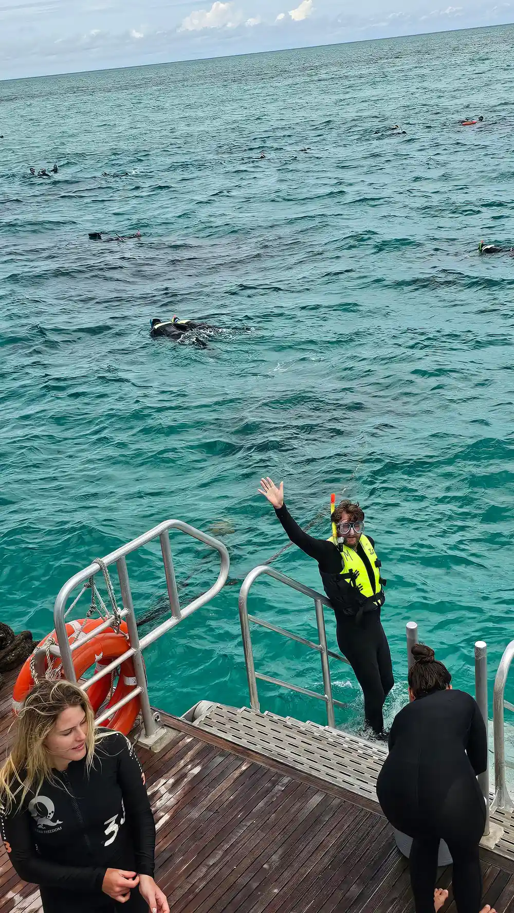 A snorkeller in the water waving beside the boat's platform