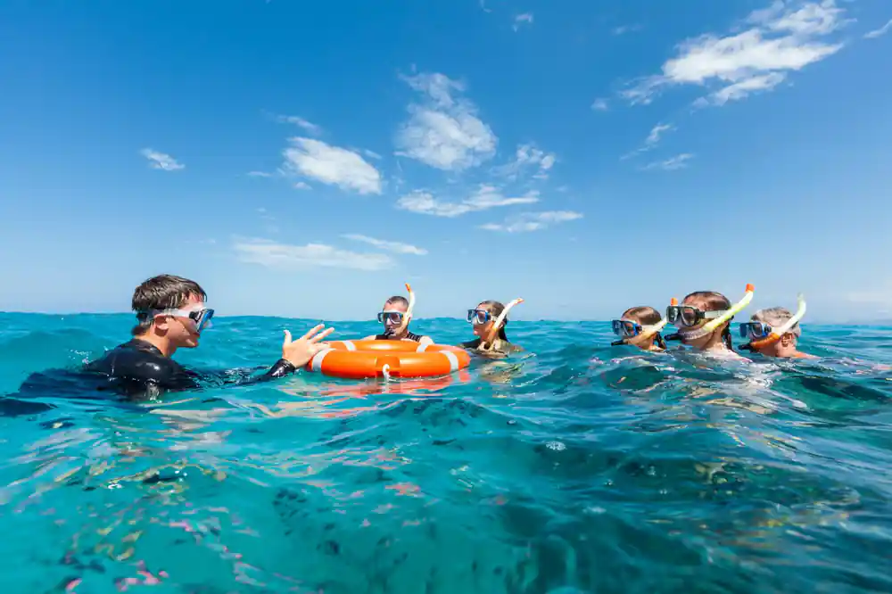 Snorkellers gathered around an orange flotation ring at the surface