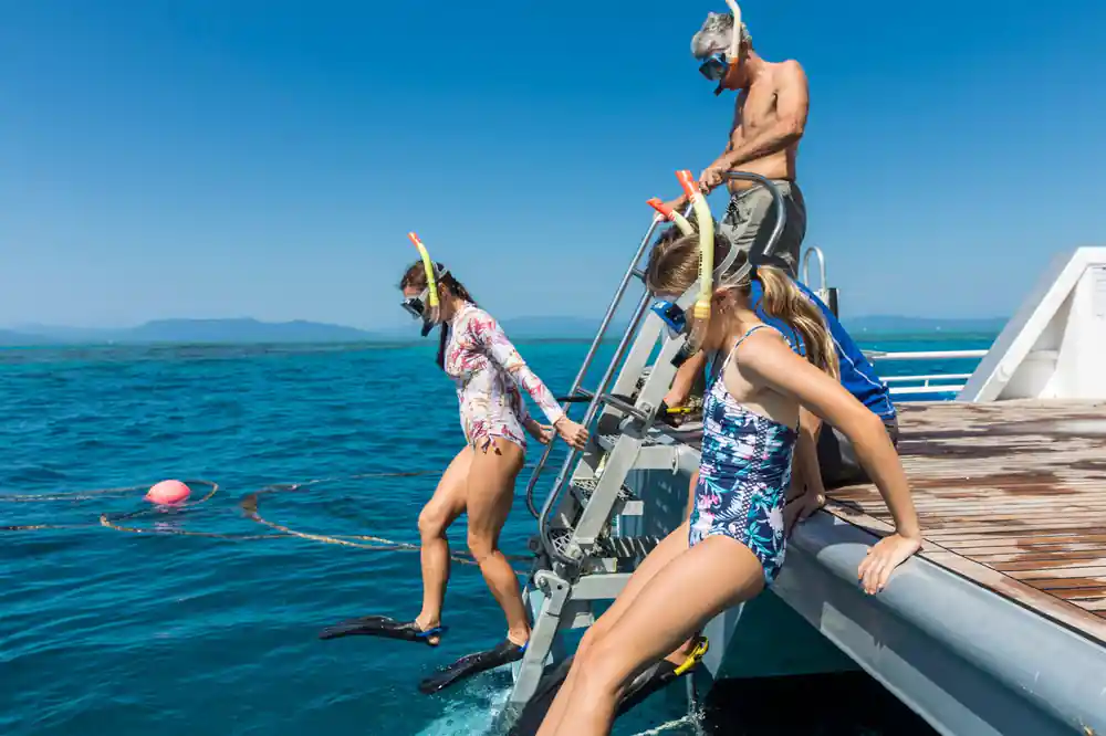 Snorkellers stepping down the boat's ladder into the water