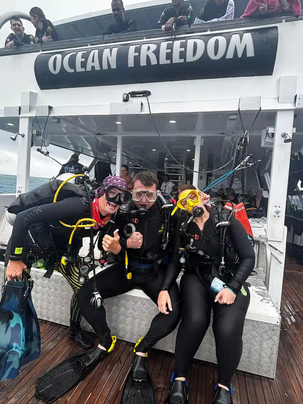 Two divers in wetsuits giving a thumbs up on the dive deck