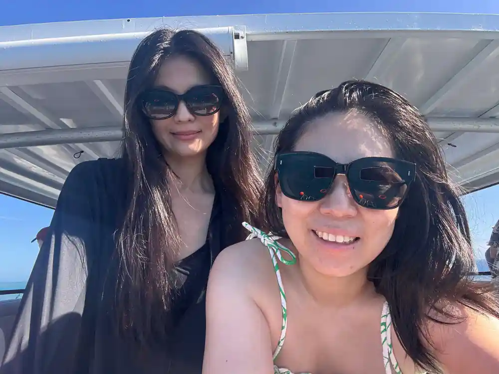 Two guests in sunglasses on the boat with the sea behind